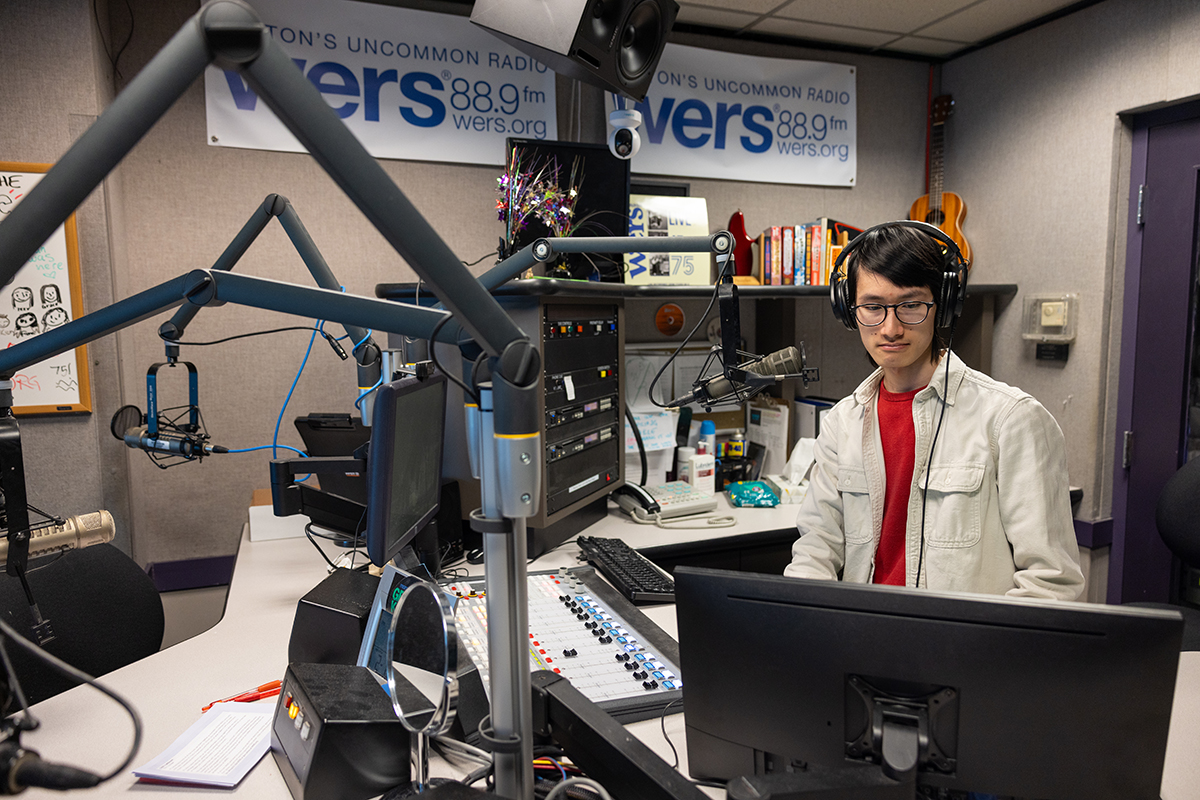 Student working at a desk and microphone at the radio station, WERS 88.8 FM