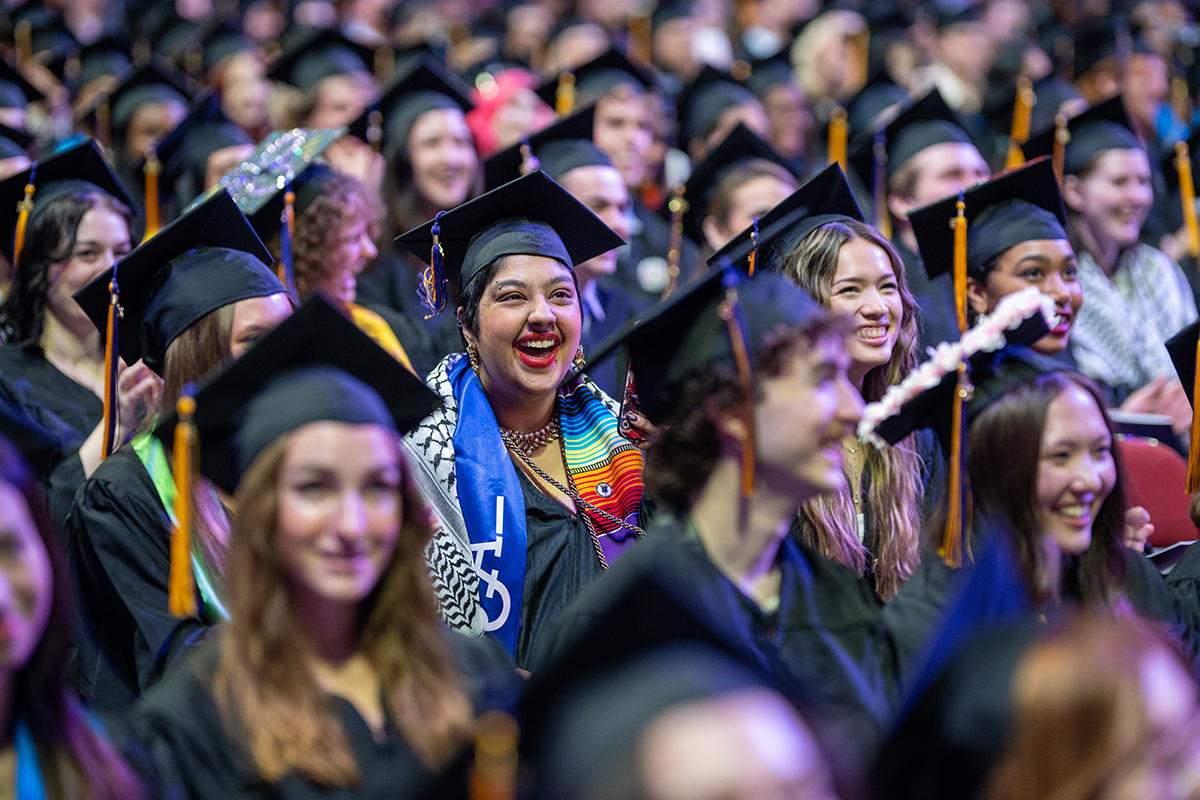 A crowd of graduating students during a Commencement ceremony, wearing their caps, gowns, and other regalia