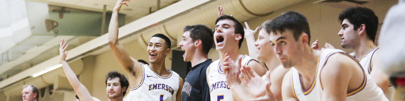 Men’s basketball players cheering on the bench.