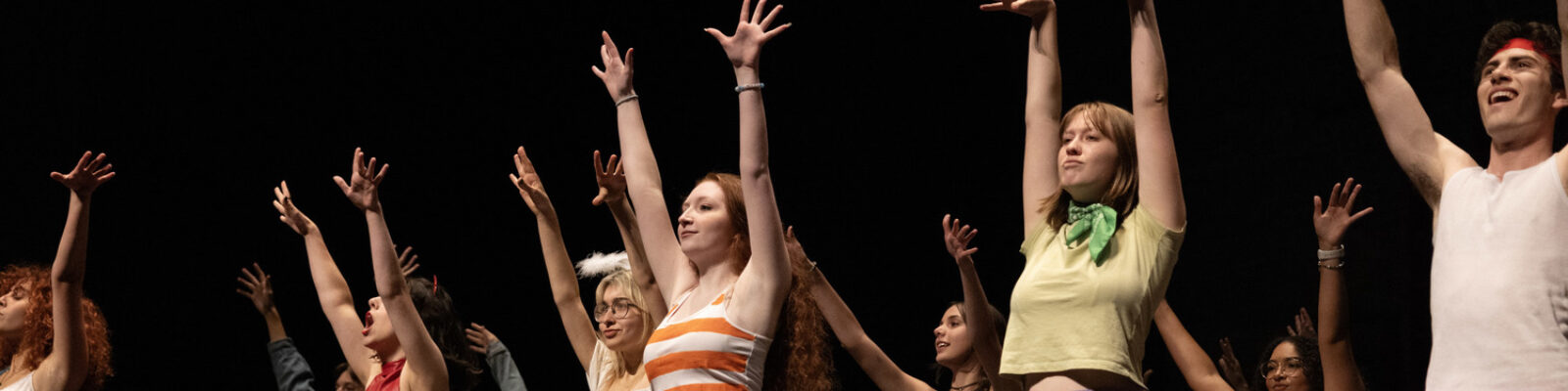 Students dancing on stage with hands in the air