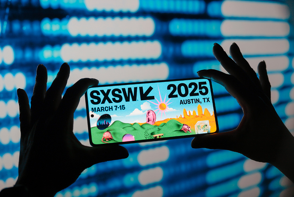 A pair of hands holding up a smartphone advertising South by Southwest (SXSW) 2025 in Austin, Texas